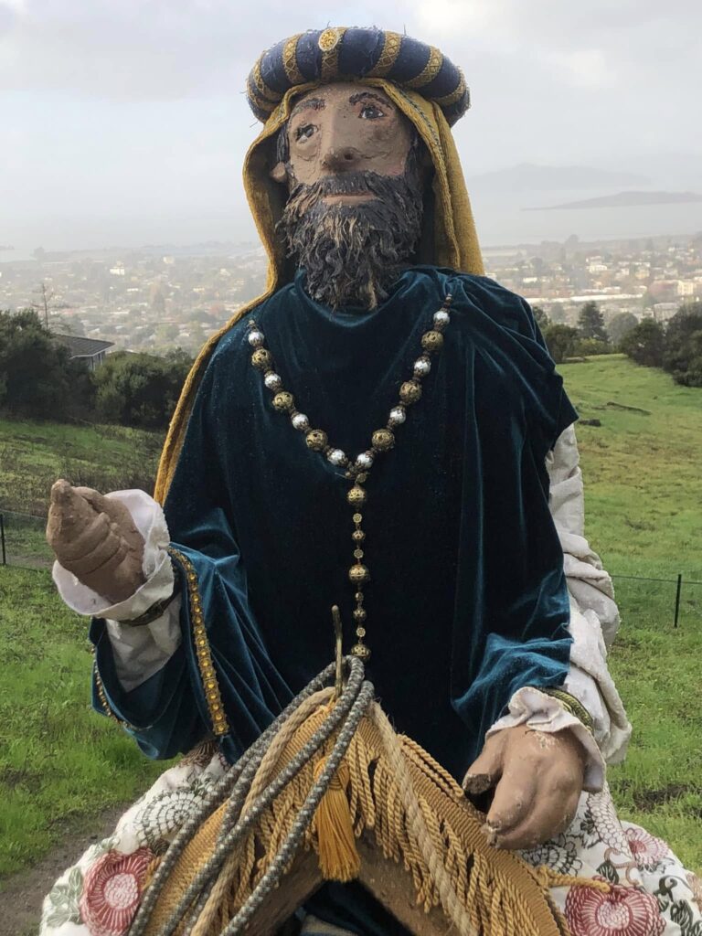 wise man figure in teal robes with el cerritto in the background