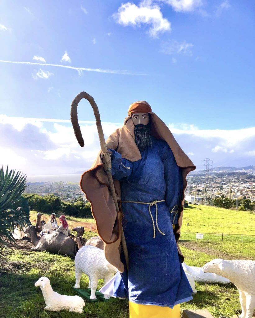 shepherd figure wearing blue robes with el cerritto in the background