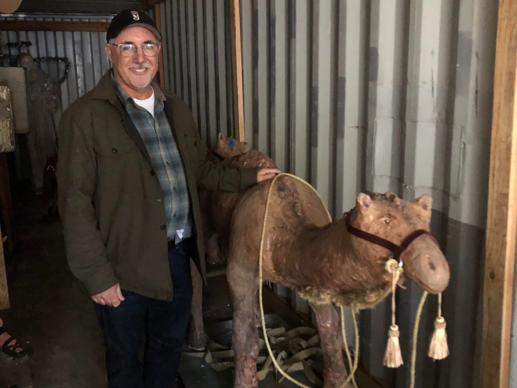 volunteer smiling for photo with camel figure in the storage container
