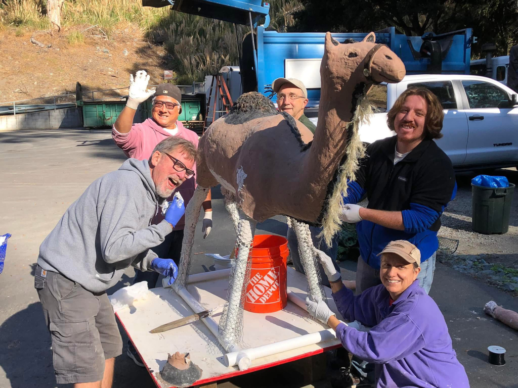 volunteers re-plastering camel figure legs